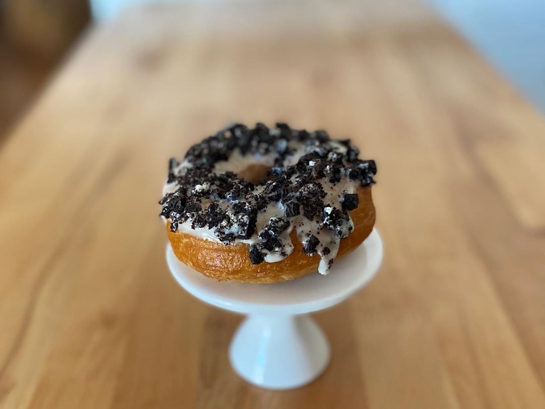 Cookies ‘n’ cream donut on white pedestal stand
