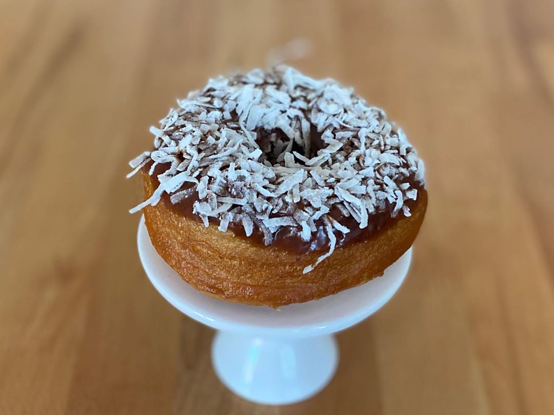 Coconu-tural Born Chocolate donut on white pedestal stand